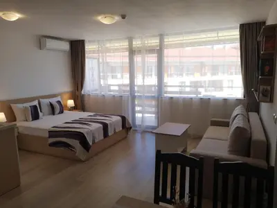 a bedroom with a bed and a couch and a window at South Beach Apartment in Nesebar