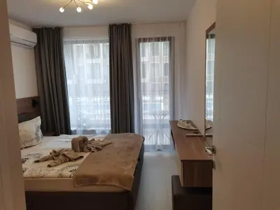a bedroom with a bed and a desk and windows at Polarstar Beach Bulgarien Sveti Vlas in Sveti Vlas