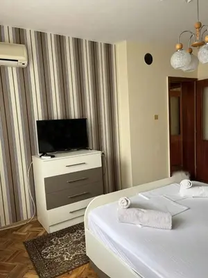 a hotel room with two beds and a flat screen tv at Apartment Geni in Pomorie
