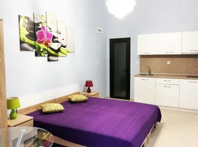 a purple bed in a room with a kitchen at Stamopolu Lux ground floor in Primorsko