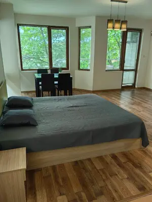a bedroom with a large bed and a table with chairs at Уютно студио в Поморие Мари in Pomorie