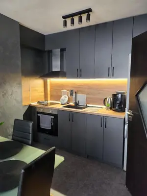 a kitchen with gray cabinets and a table with chairs at Апартамент 8 in Varna City
