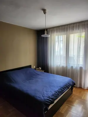 a bedroom with a blue bed and a window at Апартамент 8 in Varna City