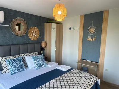 a bedroom with a bed with blue and white pillows at Wavehaven Apartment at South Bay in Varna City