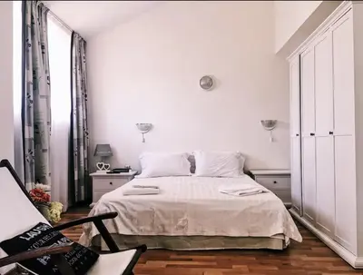a white bedroom with a bed and a chair at Spacious Modern Two-Bedroon Suite in Elit 1 Complex in Sunny Beach