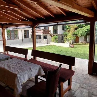 a patio with a table and chairs and a view of a yard at Коларова къща in Avren