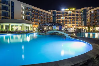 a large pool in front of a hotel at night at Tiara Beach - All Inclusive in Sunny Beach