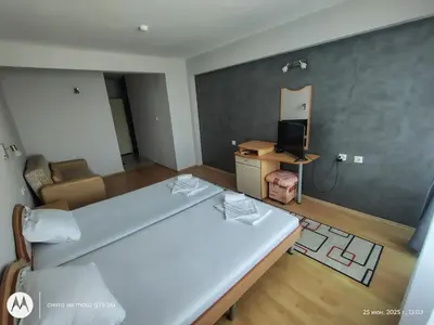 a bedroom with a large white bed and a television at Family Hotel Coral in Sozopol