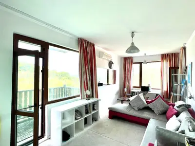 a living room with a couch and a balcony at Arkutino Beach in Burgas City