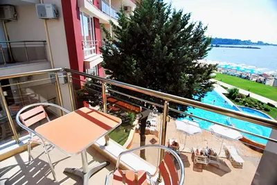 a balcony with a table and chairs and a swimming pool at Aurelia Beach Complex in Ravda