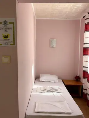 a small room with a bed with white sheets at Бунгала Мишел in Varna City
