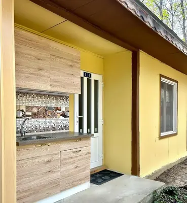 a kitchen with yellow walls and wooden cabinets at Бунгала Мишел in Varna City