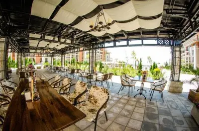 a patio with tables and chairs in a building at Prestige Fort Aparthotel - Private apartment - BSR - 2 in Sveti Vlas