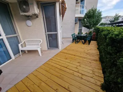 a patio with a wooden floor and a table and chairs at Апартамент БАНГЕВИ in Burgas City