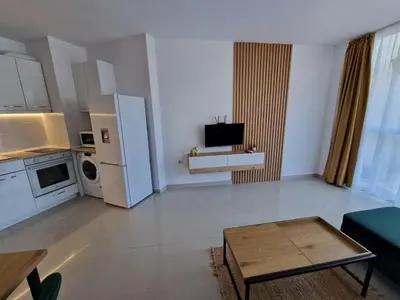 a living room with a kitchen and a living room with a table at Апартамент БАНГЕВИ in Burgas City