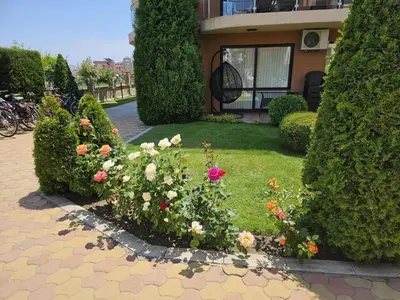 a garden with flowers and bushes in front of a house at MAGNOLIA Apartments in Ravda