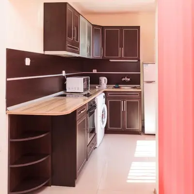 a kitchen with dark wood cabinets and a white appliance at Apartment Patriarh Evtimiy in Burgas City