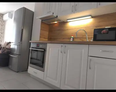 a kitchen with white cabinets and a stainless steel refrigerator at Apartment Oborishte in Burgas City