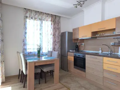 a kitchen with a wooden table with chairs and a sink at Apartment Rilska - Center and Sea Garden in Burgas City