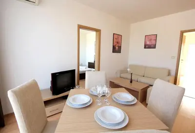 a dining room with a table with chairs and a television at Seaside 1 BR Apartment with balcony, max 4 Guests in Sunny Beach