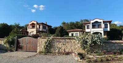 two houses behind a stone fence with a gate at къщи за гости villa Momino in Avren