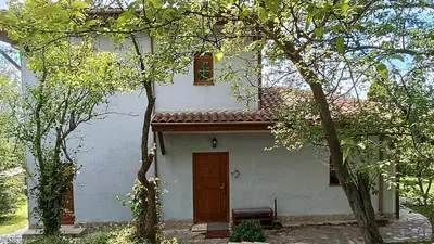 a white house with a red door and trees at къщи за гости villa Momino in Avren