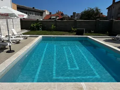 a blue swimming pool with two chairs and an umbrella at Obzor in Obzor