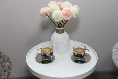 two cups of coffee on a white table with a vase at Апартамент за гости Мечта Лазур in Burgas City