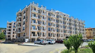 a large building with cars parked in a parking lot at Apartment mit Meeresblick Polarstar Beach 2 Zimmer Premium Apartment in Sveti Vlas
