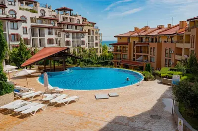 a large swimming pool with lounge chairs and buildings at Paradise Dreams Menada Apartments in Sveti Vlas