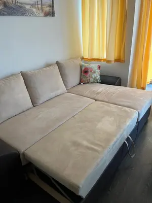 a large couch in a living room with yellow curtains at Apartment 4 Plus Burgas in Burgas City