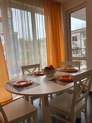 a dining room table and chairs with a table and a window at Apartment 4 Plus Burgas in Burgas City