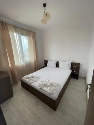 a bedroom with a bed with white sheets and a window at Вили Панорама 2 in Chernomorets