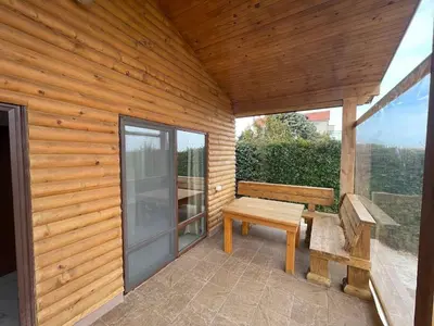 a wooden patio with a bench and a sliding glass door at Вили Панорама 2 in Chernomorets