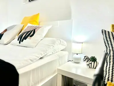 a white bed with pillows and a table with a lamp at Studio Sea Garden in Varna City