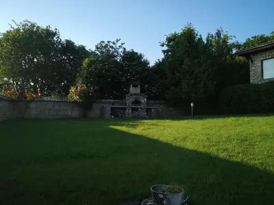 a yard with a stone wall and green grass at къща за гости villa Jurta in Avren