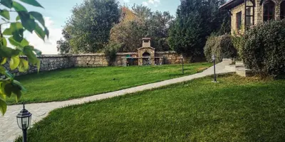 a yard with a stone wall and a house at къща за гости villa Jurta in Avren