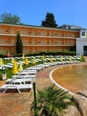 a row of lounge chairs with umbrellas in front of a building at Trakia Plaza Apartments in Sunny Beach