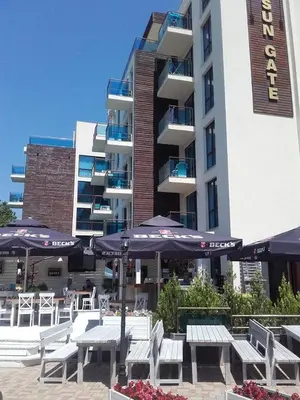 a hotel with tables and umbrellas in front of a building at SUN GATE - Kamil in Sunny Beach