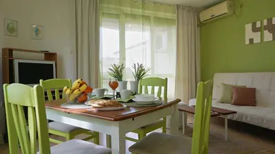 a dining room with a table and chairs with a table and a table at Апартамент Деа - Apartment Dea in Byala