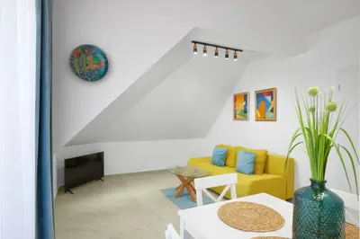 a living room with a yellow couch and a table at MAESTRA Bamboo Beach Luxury Apartment - FREE Parking in Sozopol