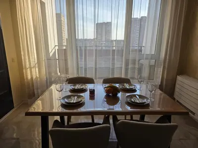 a table with chairs and plates and wine glasses in front of a window at Арена Изгрев in Burgas City