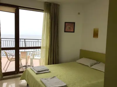 a bedroom with a bed and a balcony with a view at Apartment Slantse in Sozopol