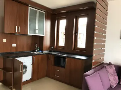 a kitchen with wooden cabinets and a washer and dryer at Apartment Slantse in Sozopol