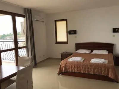 a bedroom with a bed and a table and a balcony at Apartment Slantse in Sozopol