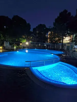 a large swimming pool with blue lighting at night at Slavi studios Aparthotel Exselsior, Sunny beach in Sunny Beach