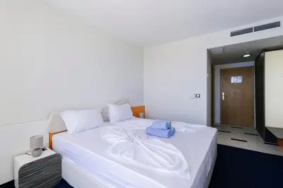 a bedroom with a white bed and a television at APOLONIS hotel in Sozopol