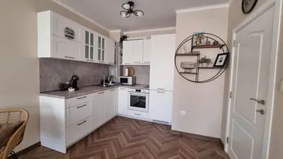 a kitchen with white cabinets and a wooden floor at АМИРА апартамент за гости - AMIRA guest apartment in Burgas City