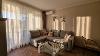 a living room with a couch and a glass table at АМИРА апартамент за гости - AMIRA guest apartment in Burgas City