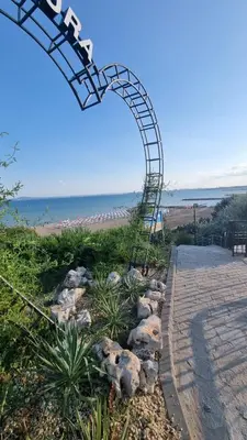 a spiral stairway leading to a beach with an archway at АМИРА апартамент за гости - AMIRA guest apartment in Burgas City